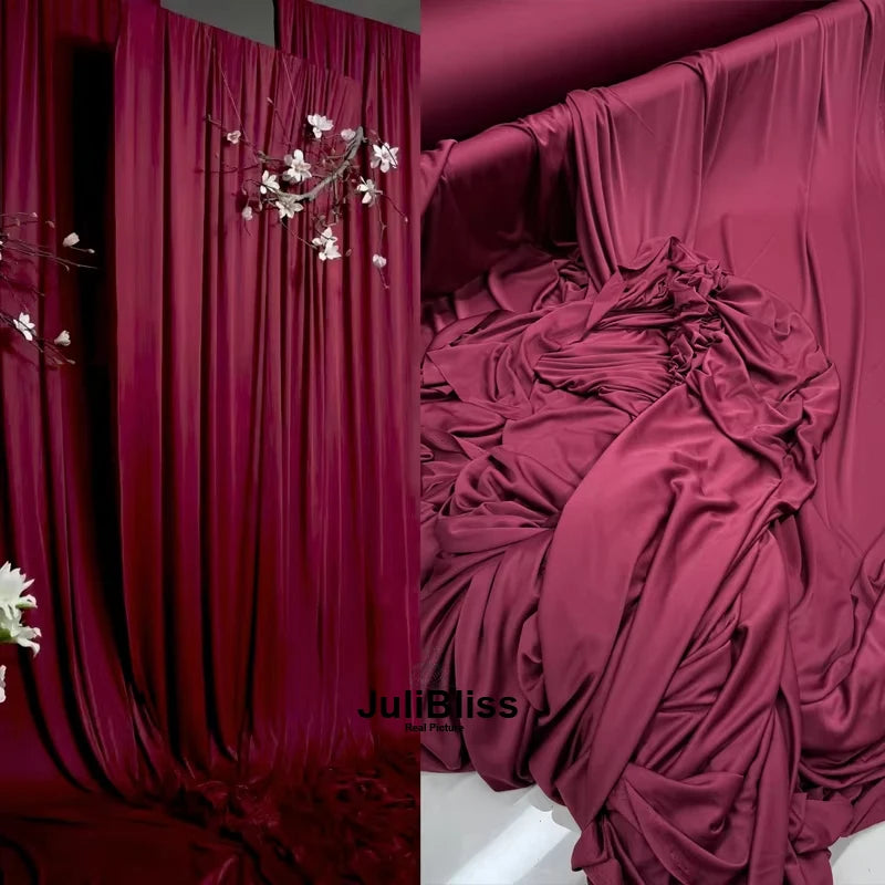 Deep magenta draping stretch fabric used as a luxurious curtain or backdrop.