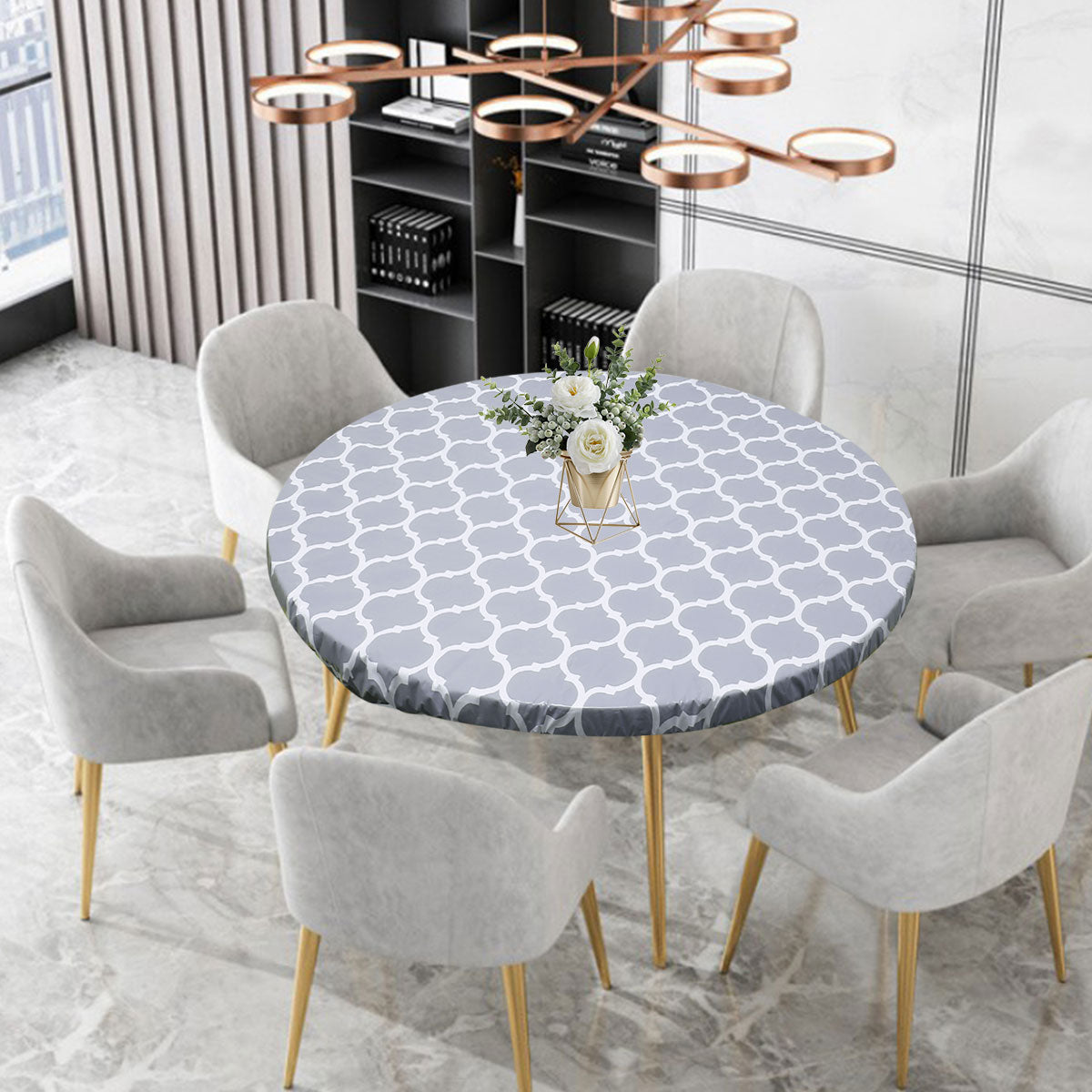 A round tablecloth with a gray and white geometric pattern is displayed on a dining table surrounded by upholstered chairs.