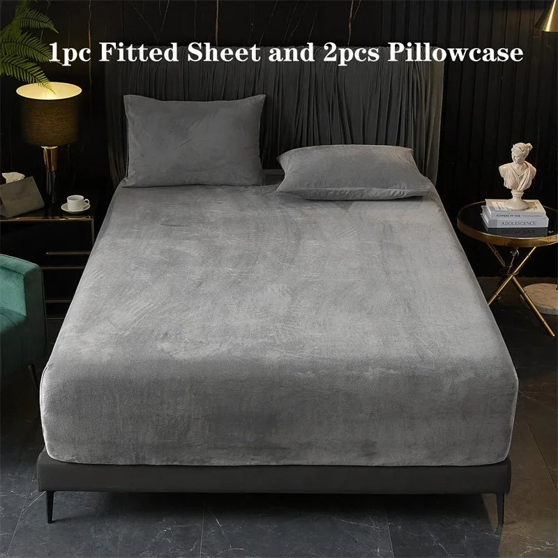 A gray fitted sheet and two pillowcases are displayed on a bed with a matching gray duvet cover.