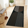 A long runner rug with black and beige geometric lines laid on a light wood floor.