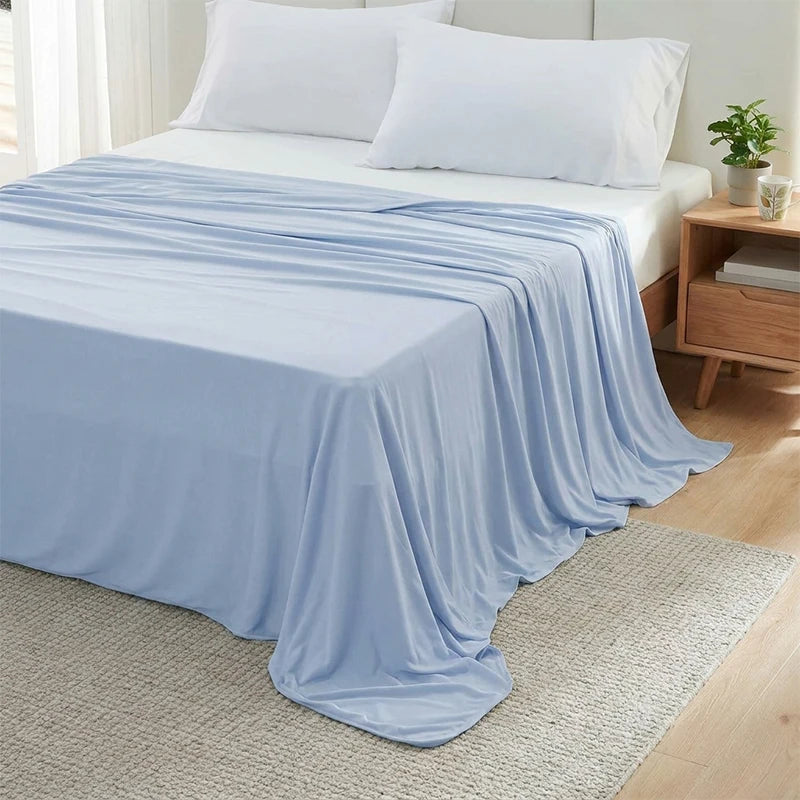 Light blue ice silk cooling blanket draped over a bed and resting on a beige rug.