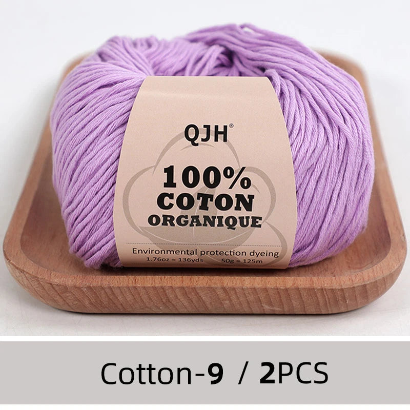 Purple QJH 100% organic cotton yarn skein on a wooden tray