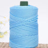 A spool of light blue crochet ice rope with a dark green core, lying on a woven surface.