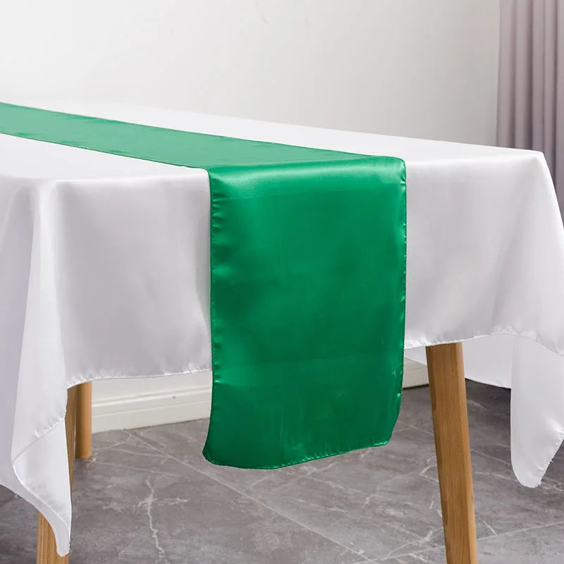 A satin green table runner draped on a white tablecloth.