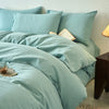 A light blue cotton yarn-dyed duvet cover with matching pillows and bedding on a bed.