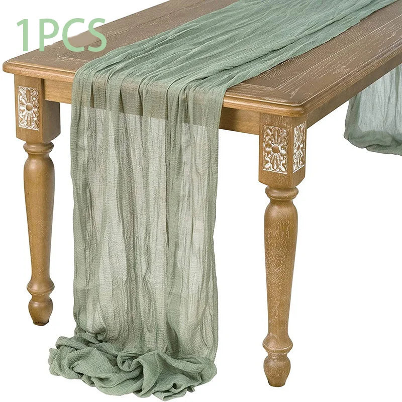 A semi-sheer sage green gauze fabric draped over a wooden table.