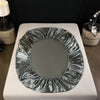 A round satin fitted sheet draped on a white surface.