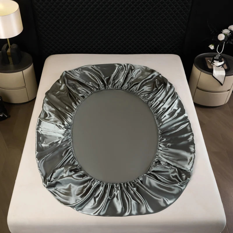 A round satin fitted sheet draped on a white surface.