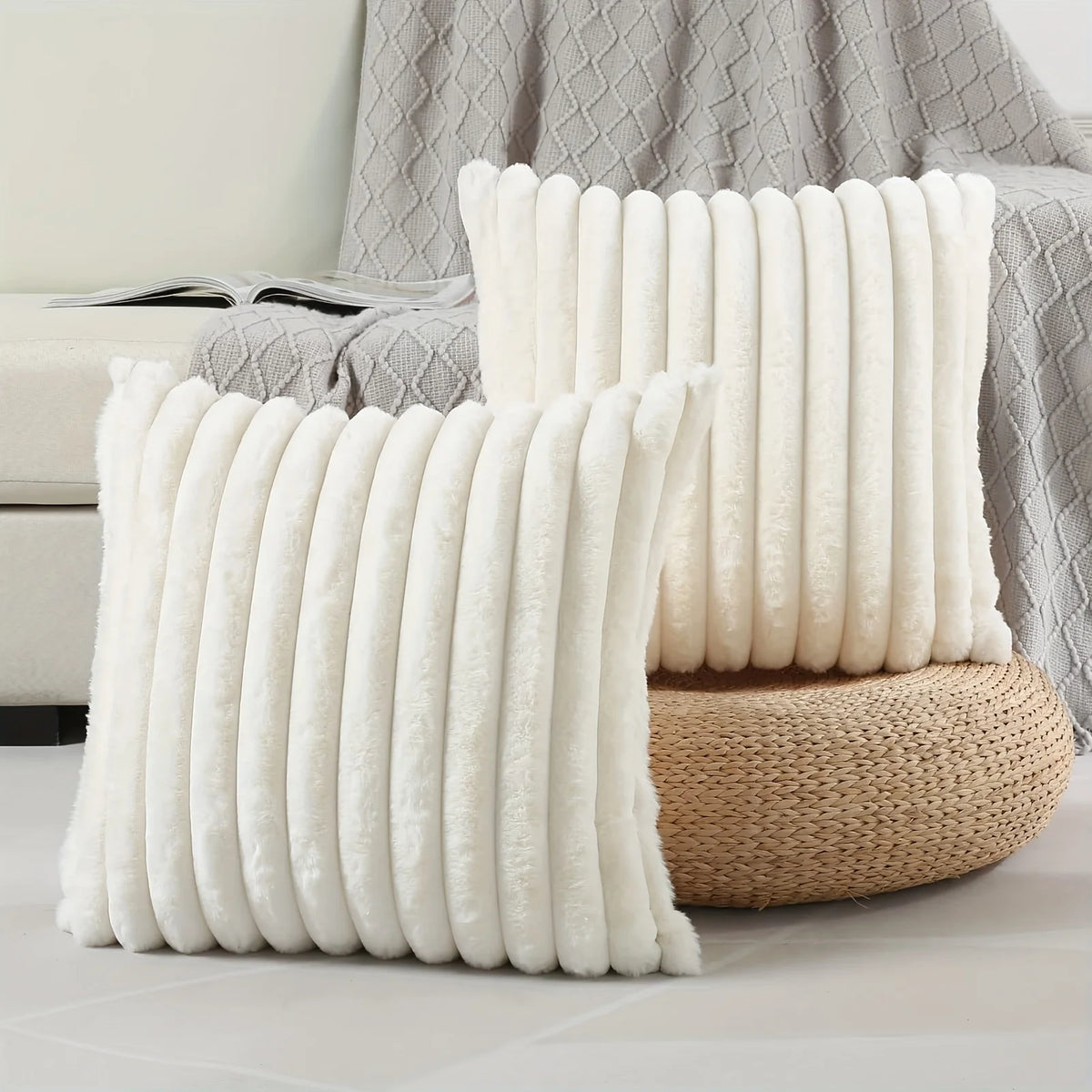 A stack of white stripe corduroy pillow covers resting on a woven basket next to a gray textured blanket.