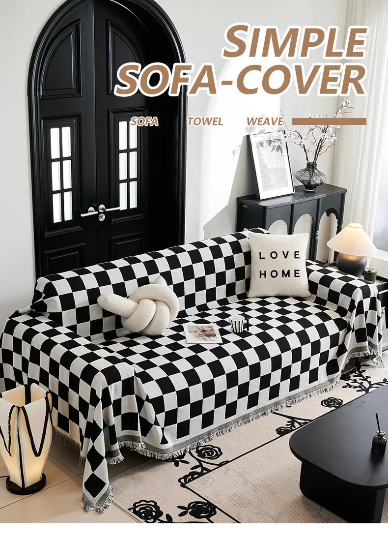A black and white checkerboard sofa slipcover displayed on a couch with a dark door in a bright room.