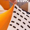 Close-up of white fabric with black polka dots layered against an orange fabric.