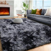 A dark gray plush long-pile area rug placed in a modern living room with a sofa and fireplace.