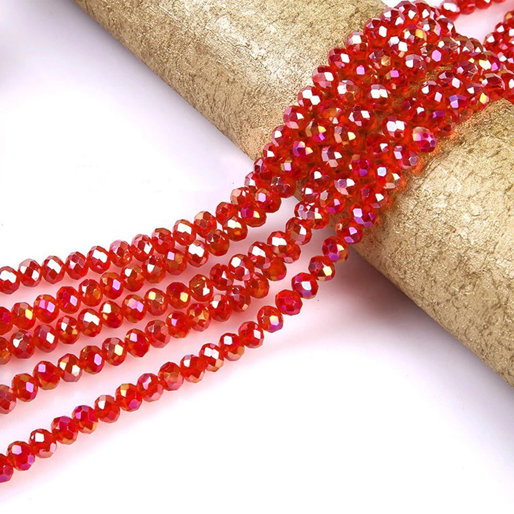 A strand of faceted, reddish-orange glass beads is unwrapped and laid out on a gold-colored fabric.