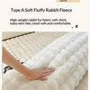 A close-up of a white rabbit fleece blanket being held, showing its fluffy texture and soft fibers.