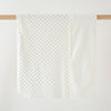 A white fleece throw blanket with a dimpled texture is hanging on a wooden rod.