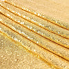 Golden sequin table runner fabric rolled up, showing shimmering gold texture and scattered sequins.
