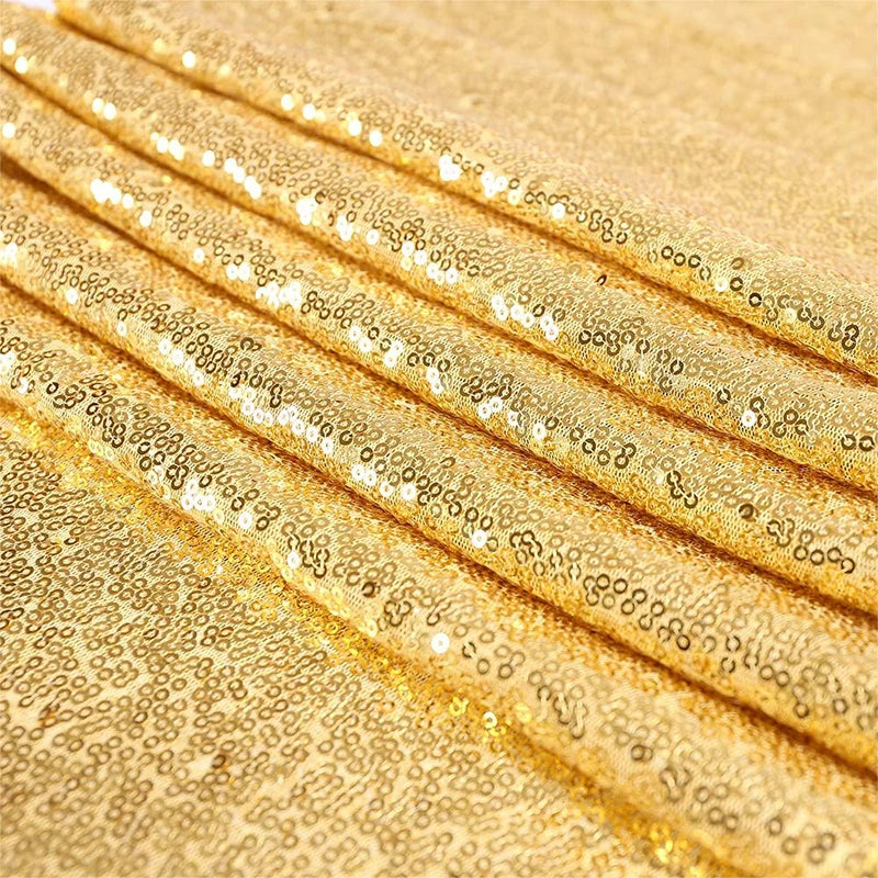 Golden sequin table runner fabric rolled up, showing shimmering gold texture and scattered sequins.