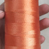 A spool of orange high tenacity polyester sewing thread with a yellow plastic core and base.