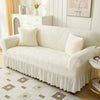 A cream jacquard elastic sofa cover with a ruffled skirt displayed in a bright room.