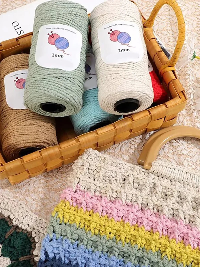 A basket filled with skeins of medium-thick hand-woven cotton yarn in various shades of green, beige, and cream.