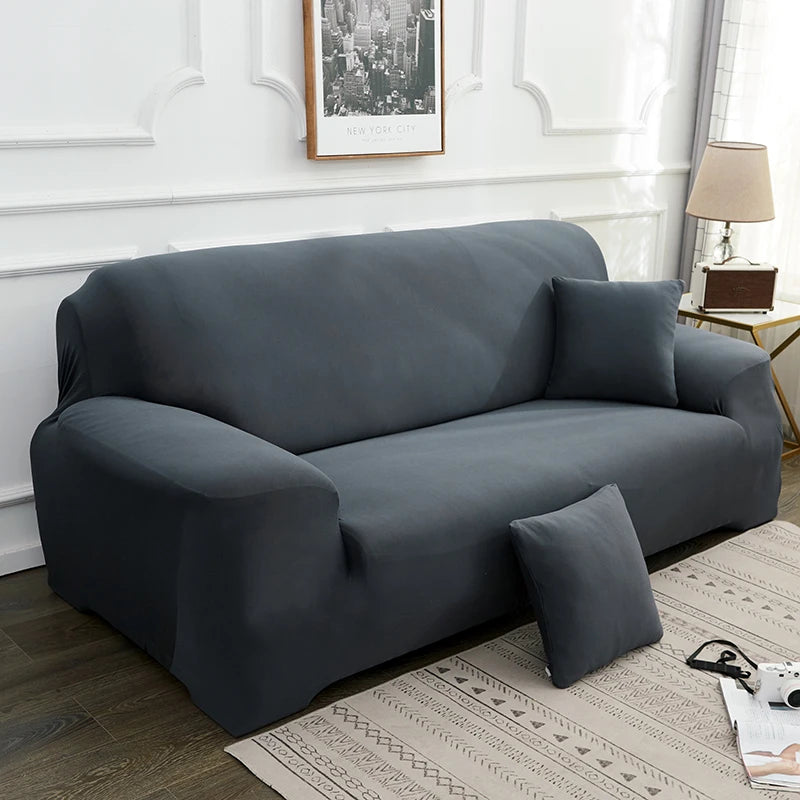 A charcoal gray elegant faux silk sofa cover placed on a light rug in a well-lit room.