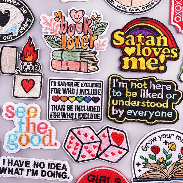 A collection of embroidered letter iron-on patches featuring various phrases like Book Lover Satan Loves Me and See The Good