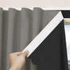 A hand is pulling a white blackout curtain panel across a gray curtain fabric.