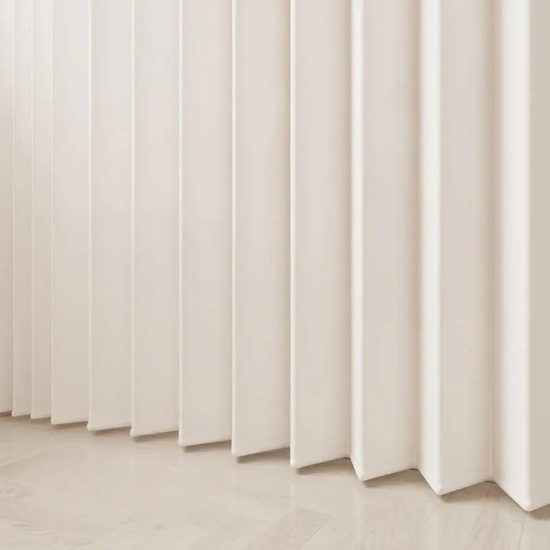 A close-up of a cream-colored, pleated fabric room divider curtain against a light wooden floor.
