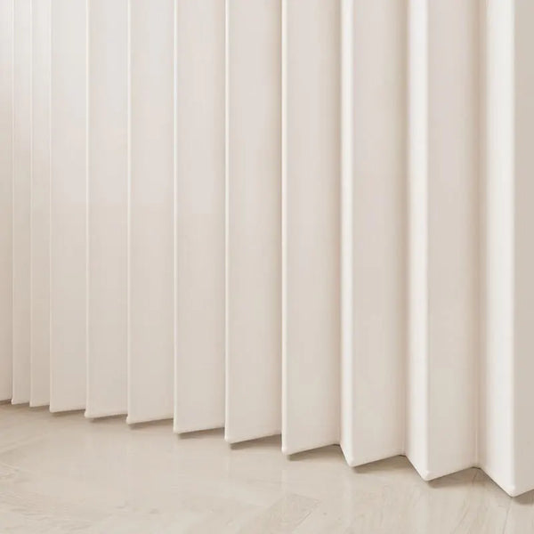 A close-up of a cream-colored, pleated fabric room divider curtain against a light wooden floor.