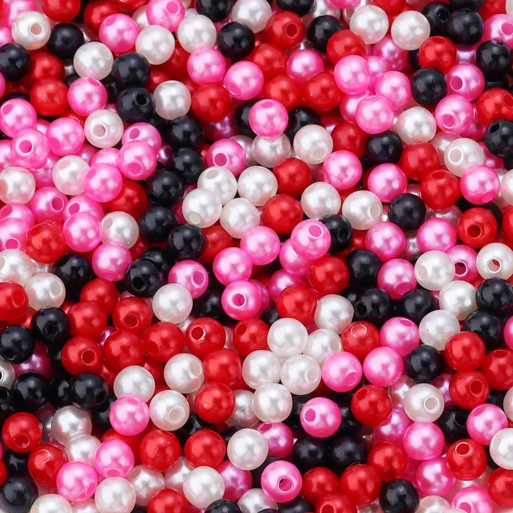 A close-up view of numerous imitation pearl beads in various shades of pink, red, white, and black.