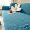 A teal textured sofa cover featuring a light blue cushion and a white decorative pillow.