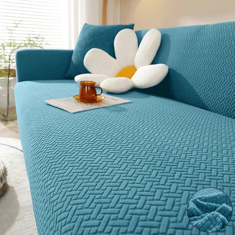 A teal textured sofa cover featuring a light blue cushion and a white decorative pillow.