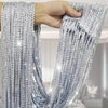 Close-up of silver beaded string curtains being held, showing the texture and hanging strands.