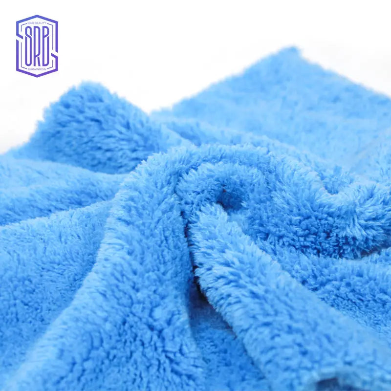 A close-up of a bright blue coral fleece microfiber cleaning cloth being folded or draped.