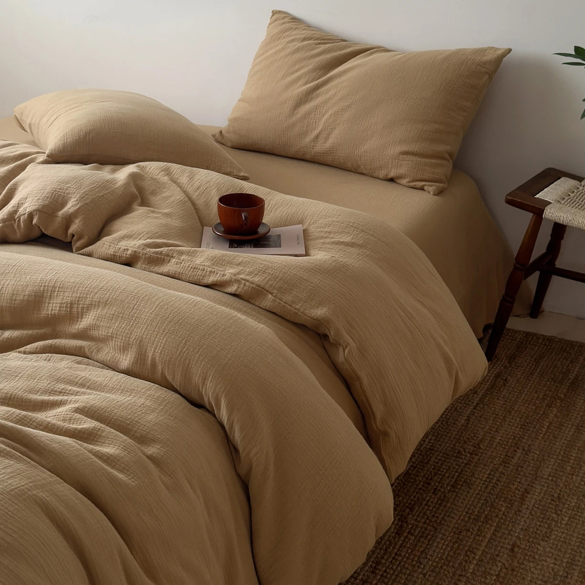 A beige duvet cover set with a matching pillow and a small brown cup resting on the fabric.
