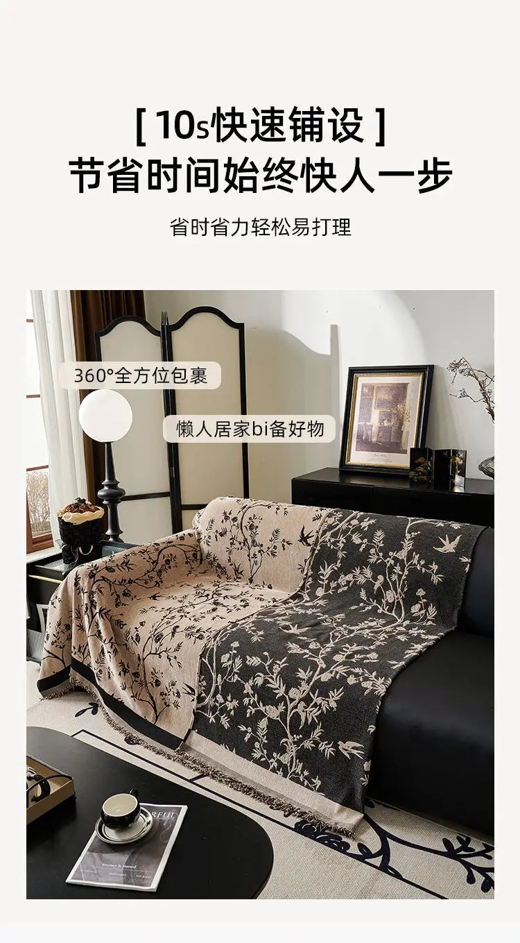A black chenille sofa slipcover draped over a dark leather sofa, featuring a floral pattern.