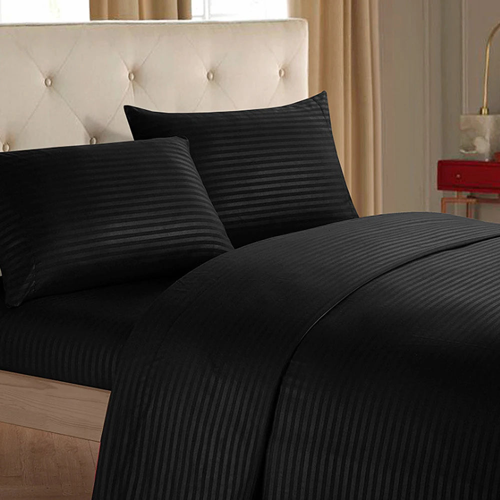 A close-up of a black striped luxury bedding set featuring pillows and a duvet on a bed.