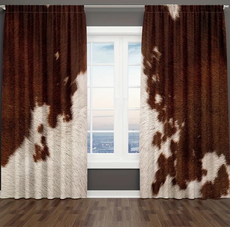 A pair of brown and white cow print curtains hanging in a window frame.