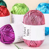 A collection of metallic pink, green, and blue yarn skeins for crochet and DIY crafts.