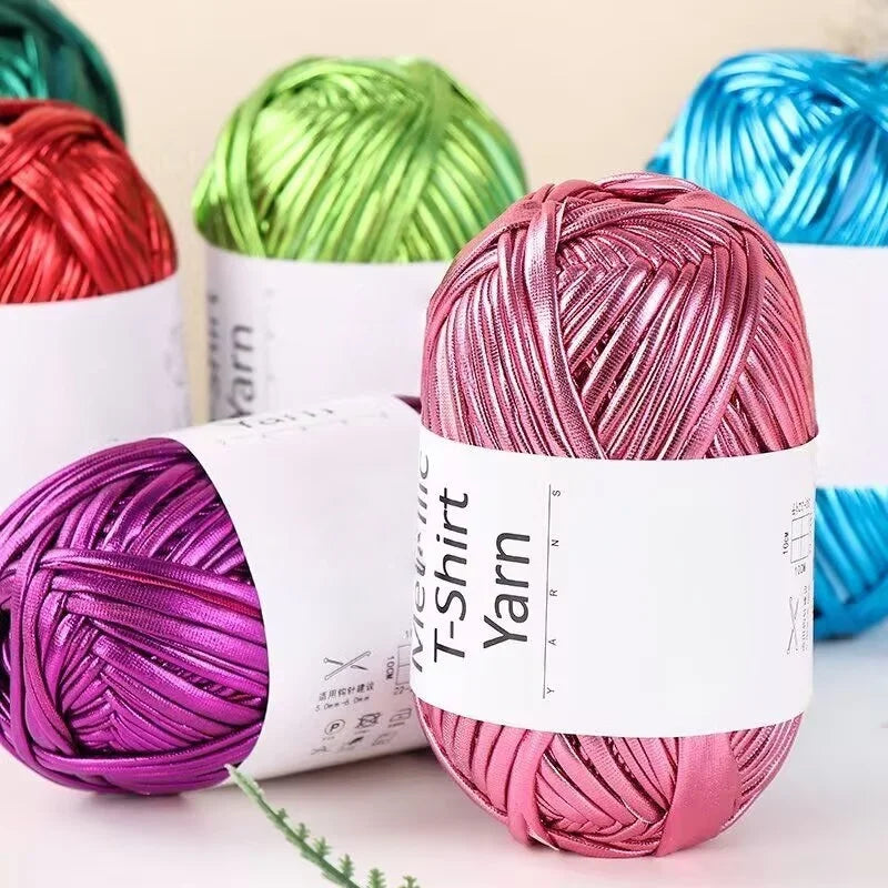 A collection of metallic pink, green, and blue yarn skeins for crochet and DIY crafts.