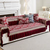 A richly embroidered red sofa cover with deep burgundy accents and patterned pillows displayed on a white upholstered sofa.