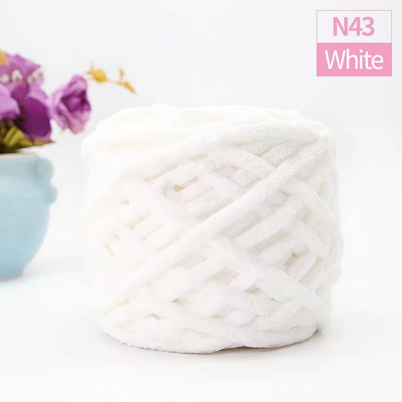 A ball of white chunky velvet knitting yarn labeled N43 White is shown next to a purple flower.