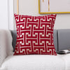 A square red and off-white geometric jacquard lumbar pillow cover resting on a gray sofa.