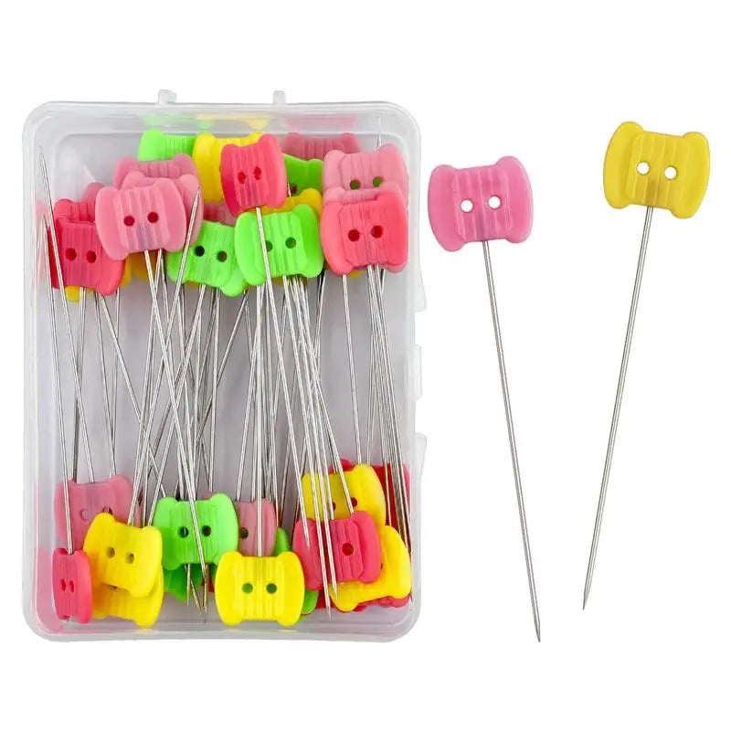 A clear plastic box containing numerous nickel-plated dressmaking pins with colorful heads.
