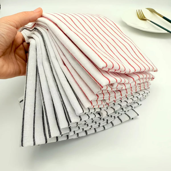 A hand holds a stack of striped cleaning cloths in white, red, and black patterns.