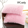 One piece of pink faux fur pillow covers displayed on a brown leather chair.