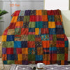A colorful patchwork throw blanket featuring a grid pattern of various floral and solid colored fabrics.