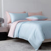 A light blue luxury bamboo duvet cover set displayed on a bed with pink accents and white walls.