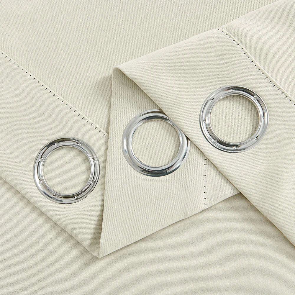 Silver grommet curtain rings displayed on a beige fabric swatch.