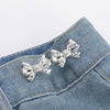 Silver bow-shaped brooches clipped onto a blue denim fabric